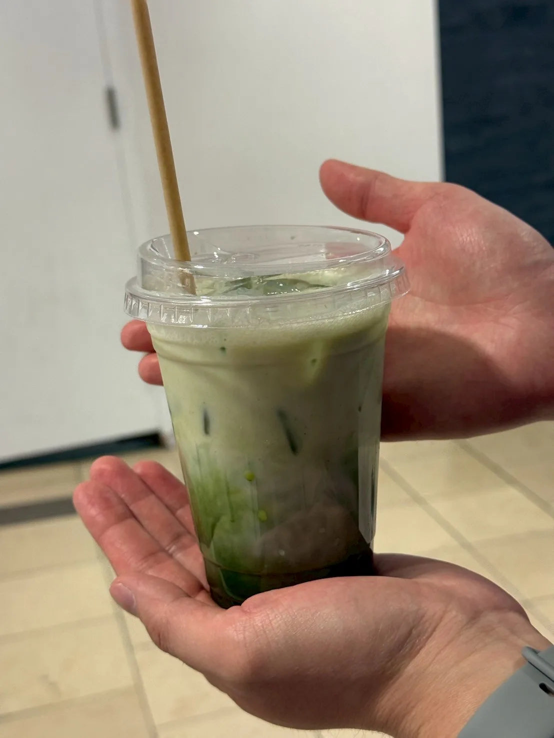 Iced matcha latte held in hand