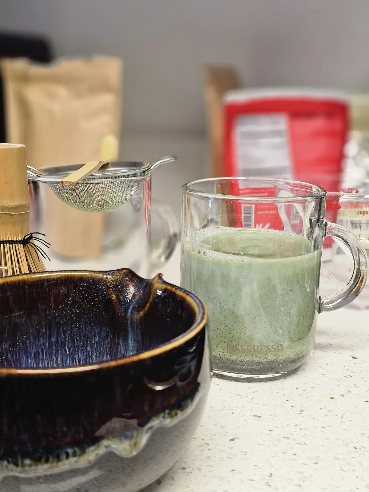Matcha latte with whisk and ceramic bowl on a shelf